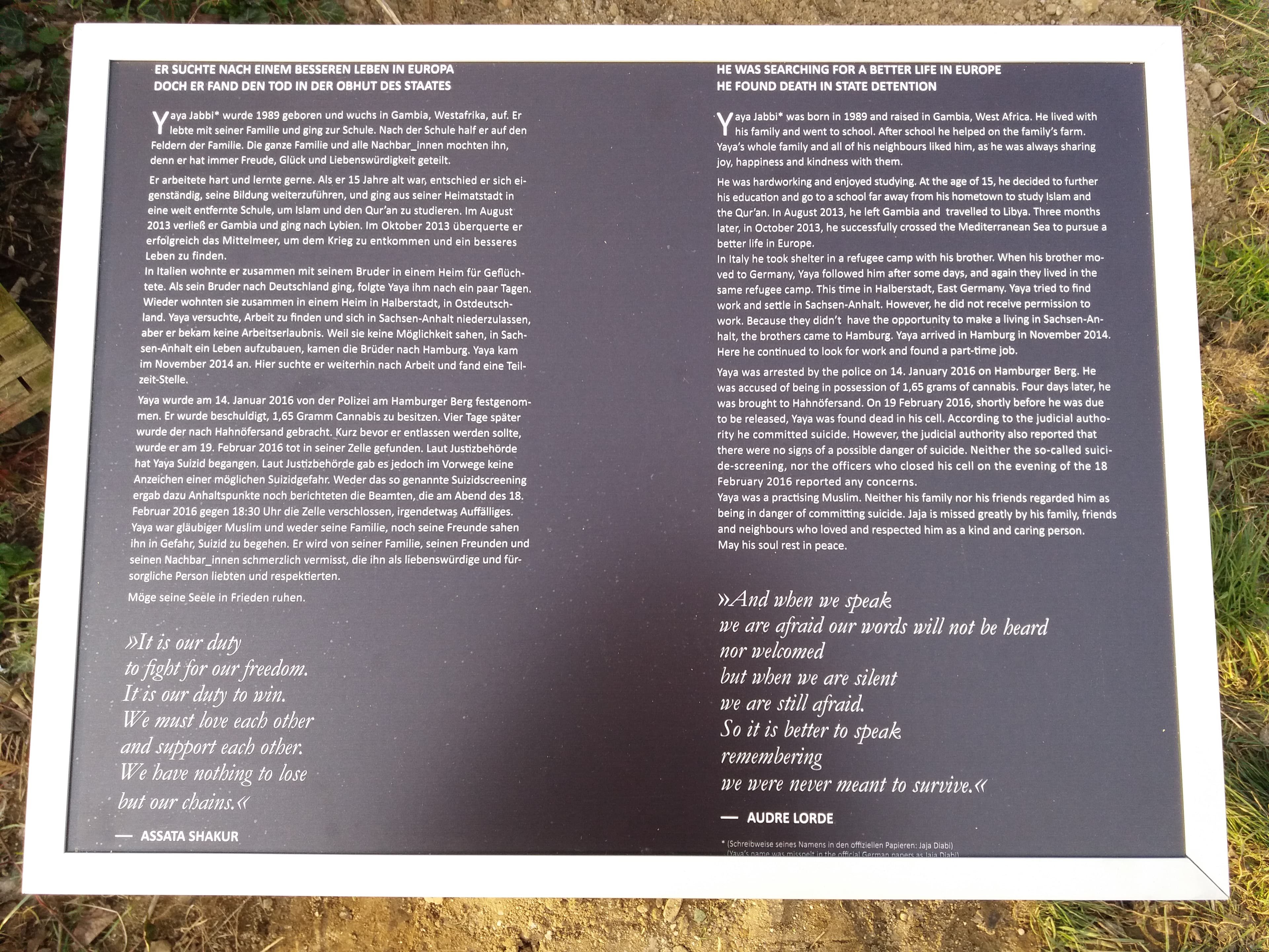 A plaque qith text: HE WAS SEARCHING FOR A BETTER LIFE IN EUROPE, HE FOUND DEATH IN STATE DETENTION Yaya labbit was born in 1989 and raised in Gambia, West Africa. He lived with his family and went to school. After school he helped on the family's farm. Yaya's whole family and all of his neighbours liked him, as he was always sharing joy, happiness and kindness with them. He was hardworking and enjoyed studying. At the age of 15, he decided to further his education and go to a school far away from his hometown to study Islam and the Quran. In August 2013, he left Gambia and travelled to Libya. Three months later, in October 2013, he successfully crossed the Mediterranean Sea to pursue a better life in Europe. In Italy he took shelter in a refugee camp with his brother. When his brother mo ved to Germany, Yaya followed him after some days, and again they lived in the same refugee camp. This time in Halberstadt, East Germany. Yaya tried to find work and settle in Sachsen-Anhalt. However, he did not receive permission to work. Because they didn't have the opportunity to make a living in Sachsen-An-halt, the brothers came to Hamburg. Yaya arrived in Hamburg in November 2014. Here he continued to look for work and found a part-time job, Yaya was arrested by the police on 14. January 2016 on Hamburger Berg. He was accused of being in possession of 1,65 grams of cannabis. Four days later, he was brought to Hahnöfersand. On 19 February 2016, shortly before he was due to be released, Yaya was found dead in his cell. According to the judicial authority he committed suicide. However, the judicial authority also reported that there were no signs of a possible danger of suicide. Neither the so-called suici-de-screening, nor the officers who closed his cell on the evening of the 18 February 2016 reported any concerns. Yaya was a practising Muslim. Neither his family nor his friends regarded him as being in danger of committing suicide. Jaja is missed greatly by his family, friends and neighbours who loved and respected him as a kind and caring person. May his soul rest in peace. »And when we speak we are afraid our words will not be beard nor welcomed but when we are silent we are still afraid. So it is better to speak remembering we were never meant to survive.« - AUDRE LORDE